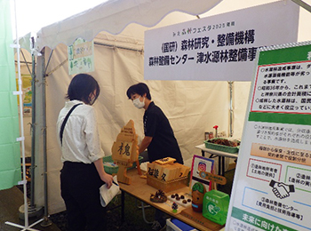 事業のパネルも置かれたテント内で受付する女性