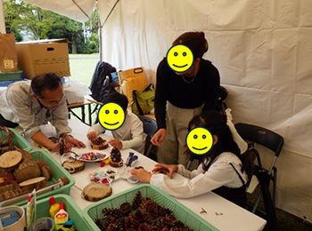 テント内で職員と木工作品制作を行う母親と娘2人