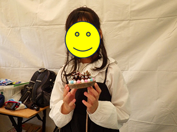 テント内で工作した作品を見せる10歳くらいの少女