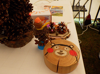 木工工作成果の松ぼっくり製タワーとキャラクター。木片に、くまもんの顔