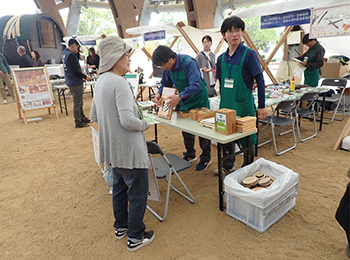 イベントブースで木へんのつく漢字クイズに立ったまま挑戦する灰色の服の女性