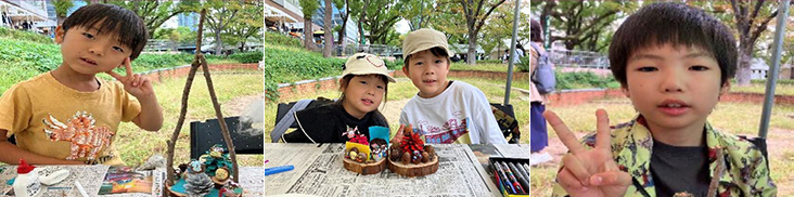 左：ピースサインをして首をかしげる恐竜模様黄色シャツ男の幼児３歳くらい。右手に木工工作成果着色松ぼっくりなど。中央：兄弟らしき４～５歳の幼児二人黒シャツ灰色シャツ。手前に輪切り木片コースターは上にどんぐり等着色し装飾。右：ピースサイン白に柄模様シャツ男の幼児３歳くらい。手前に木工工作成果どんぐりにマンガのような目玉書き入