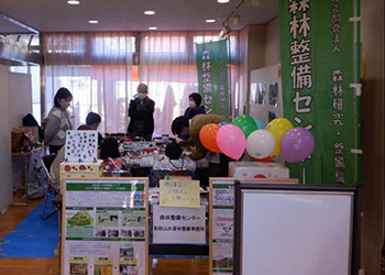 屋内の整備センターブース手前に事業パネル奥で4，5人工作　右にセンター旗