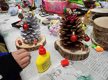 松ぼっくりクリスマスツリーの完成例2つ。左側白く着色。手前に黄色い木工ボンド。赤い球体で装飾